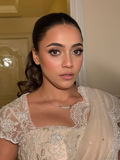 A more dramatic portrait of the bride. The lighting highlights the contours of her face and the glossy finish on her skin, showing the versatility of a "glowing" look.