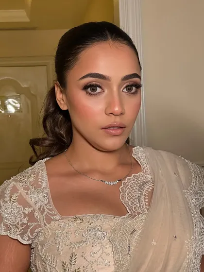 A more dramatic portrait of the bride. The lighting highlights the contours of her face and the glossy finish on her skin, showing the versatility of a "glowing" look.