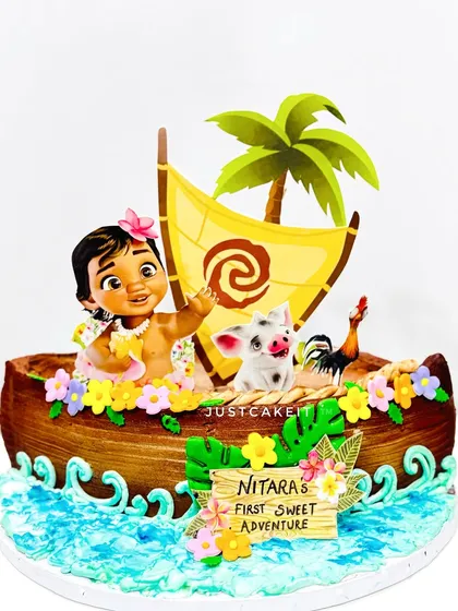 A Baby Moana cake adventure, with a cream-finished boat and minimal fondant accents. The waves and tropical details bring the ocean scene to life.