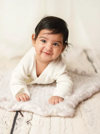 A big, proud smile from this little guy during his tummy time session. He's clearly happy to show off his new skills.