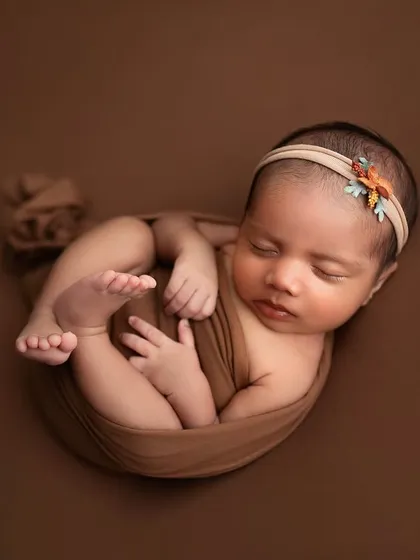 A monochrome color scheme can be incredibly powerful. In this shot, we used various shades of brown for the wrap and background to create a warm, earthy, and timeless newborn portrait.