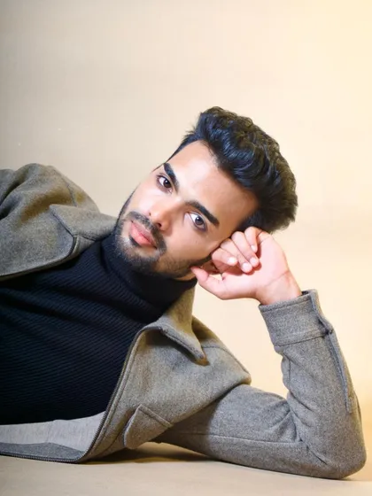 A close-up portrait with the model reclining, offering an intimate and unconventional angle. This shot highlights the model's expression and the textures of the felt jacket and ribbed turtleneck.