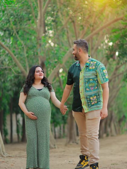 A classic couple's pose, holding hands and looking at each other. The casual outfits and the natural park setting create a relaxed and intimate feel.