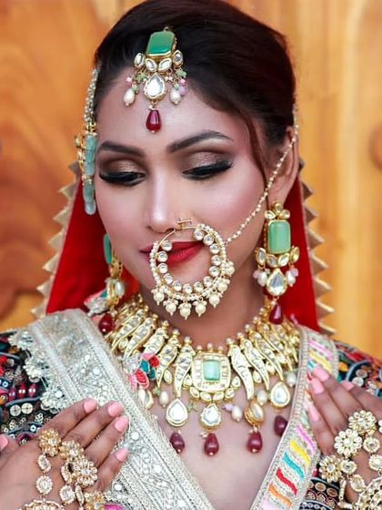 A close-up of a bride wearing a multi-colored Kundan set inspired by traditional designs. The large nath and mint-green stones make this a standout piece.