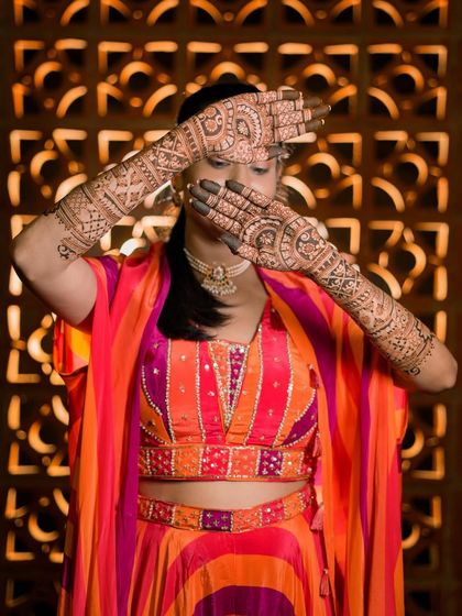 Rupa striking a classic bridal pose, her hands hiding her face, showcasing the intricate back-of-hand design.