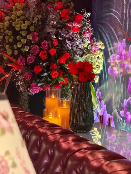 A detail from a mood-lit lounge corner. The warm glow of the candles and the rich red of the roses create a romantic and intimate atmosphere.