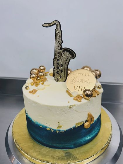 This cake was for a 13-year-old saxophonist! The design is simple and elegant, with a deep blue and white base, gold details, and a custom saxophone topper.