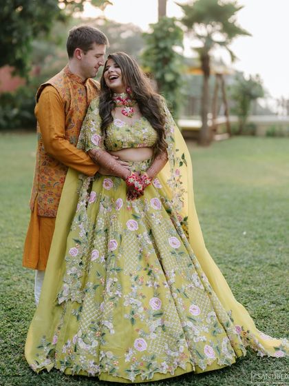 A happy, candid shot of the couple, with the groom embracing the bride, capturing a moment of pure joy during their outdoor Mehendi.
