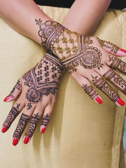 A chic and modern design on the back of the hands. The geometric jaal pattern and floral motifs are stylish and contemporary, beautifully complemented by the client's red nails.