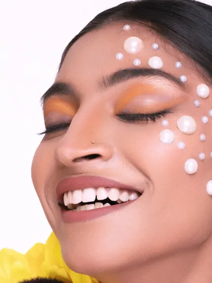 A close-up on happiness. This shot from our sunflower and pearls series captures a radiant smile, showcasing the beautiful contrast between the warm makeup and the cool pearls.