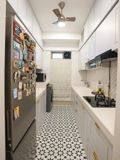 Another view of the galley kitchen, showing the herringbone pattern of the backsplash tiles, which adds subtle texture to the monochrome design.