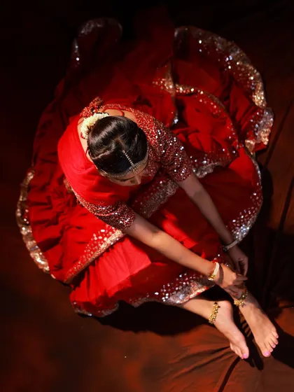 A detail-oriented shot focusing on the model fastening her anklet. This adds a narrative, 'getting ready' element to the photoshoot.
