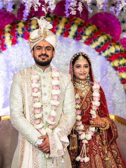 A formal portrait of the bride and groom on their wedding stage. This shot captures their regal outfits and the grandeur of the wedding decor.