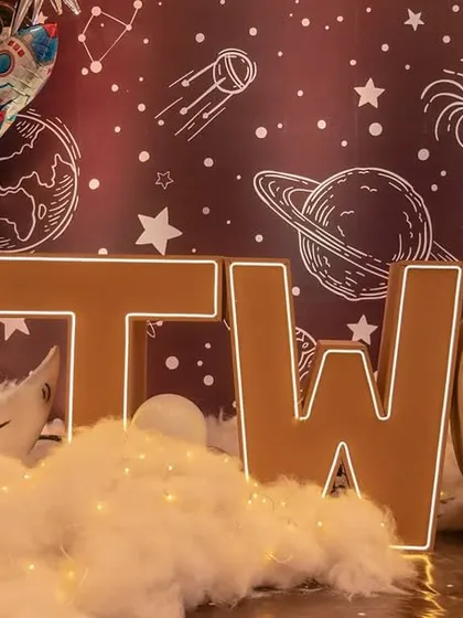 The main stage for the space-themed party, with a 'TWO' marquee sign, a moon prop, and a rocket ship taking off.