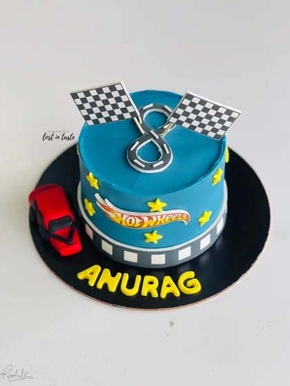 A Hot Wheels themed cake for a young racing fan. This design features a vibrant blue buttercream, the Hot Wheels logo, checkered flags, and a toy car.