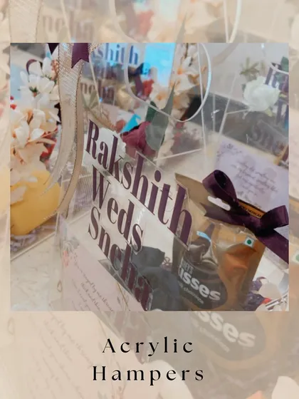 A closer look at our custom acrylic invitation hampers. The transparent design beautifully showcases the curated items inside, while the personalized text with the couple's names adds a modern, elegant touch.