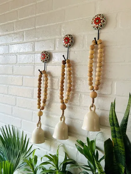 A side view of our classic white boho beaded ceramic bells. The combination of natural wooden beads, jute twine, and ivory ceramic creates a rustic and serene atmosphere, perfect for your balcony or garden.