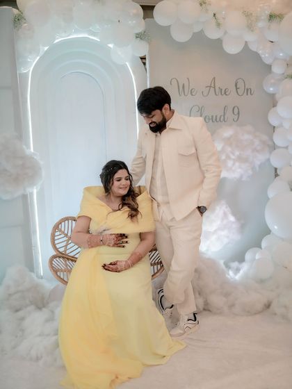 The parents-to-be sharing a sweet moment in their 'Cloud 9' wonderland. The all-white decor with a pop of yellow from the mom-to-be's dress looks absolutely heavenly.