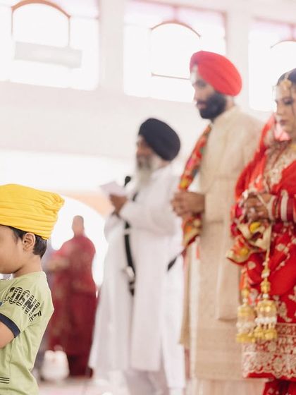 A young boy stands in prayer alongside the couple during their Anand Karaj. This powerful image captures the passing of faith and tradition through generations.