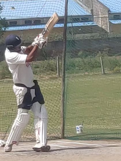A batsman executes a perfect follow-through after a powerful shot in the nets. This is a sign of excellent technique and timing.
