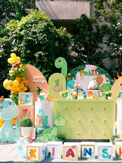 This outdoor dinosaur theme was so much fun to create. We used bright, friendly colors and cute dinosaur cutouts to make it feel playful and exciting for a 'One-O-Saurus' birthday, complete with a custom dessert table and name blocks.