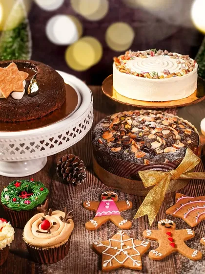 A beautiful spread of Christmas cakes and cookies, with warm bokeh lights in the background. This shot captures the magical, cozy feeling of a holiday bakery.
