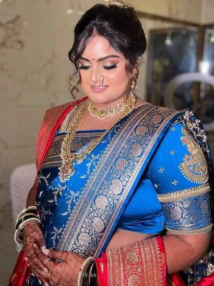 My bride Divya, glowing for her Maharashtrian engagement. We created two traditional looks for her, one in a stunning royal blue saree and another in a beautiful orange one, both featuring classic bold eyes and radiant skin.
