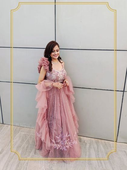 A happy client looking stunning in a modern pink gown with a ruffled dupatta and intricate embroidery. This is a perfect example of a high-fashion rental for a special occasion.