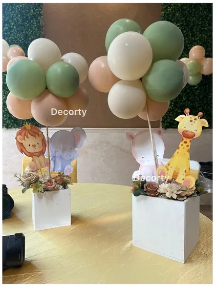 Cute jungle-themed centerpieces with cartoon animal cutouts and small balloon bouquets.