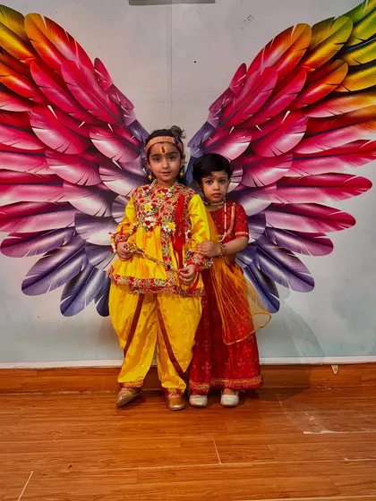 Dressed in an ornate yellow dhoti and jewelry, this little Krishna stands proudly with his Radha.