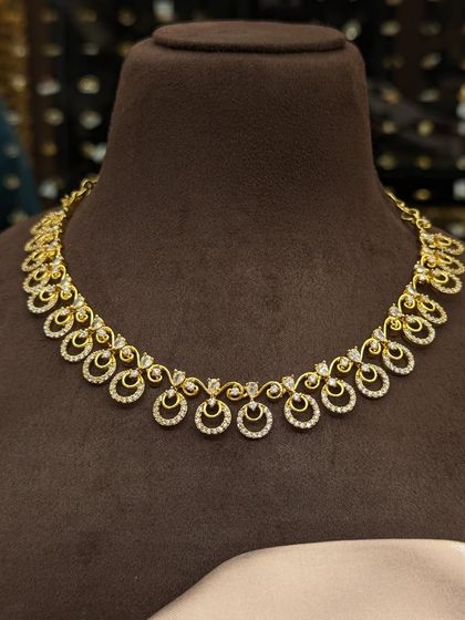 A beautiful and dainty necklace with sparkling AD stones. The design features small crescent and circle motifs, adding a touch of sparkle for any occasion.