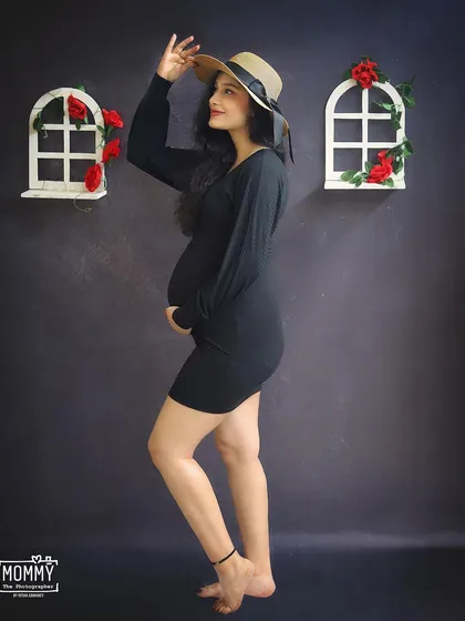 A chic and stylish solo maternity portrait. The mom-to-be rocks a simple black dress and a hat, showing that you can bring your own personal style to the studio shoot.