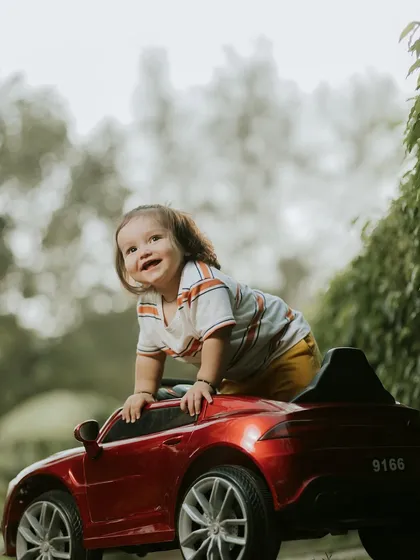 A happy little adventurer enjoying a ride in his red toy car. Outdoor shoots like this allow for so much natural joy and movement.