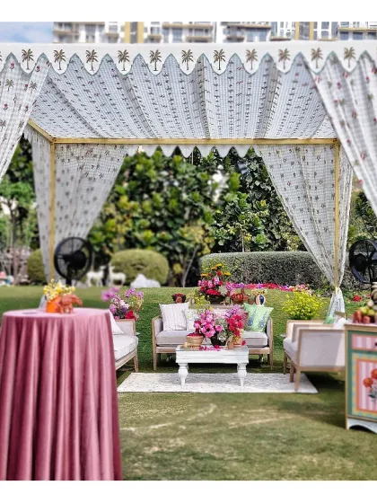 Every detail matters in creating an immersive experience. This shot highlights a cozy seating arrangement under a block-printed canopy, complete with a hand-painted cabinet and lush florals, showing how we layer textures and colors for a rich, detailed look.