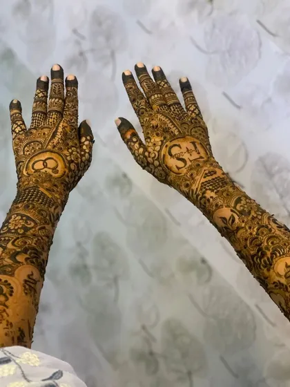 This design for a bride features interlocking rings and initials, a beautiful way to personalize your wedding mehendi. The surrounding patterns are dense and traditional.