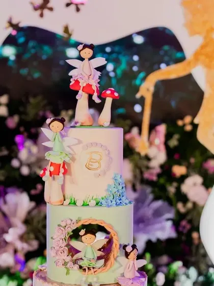 A close-up of the exquisitely detailed cake from an enchanted garden party. The cake features delicate, handcrafted sugar fairies and mushrooms, perfectly matching the magical theme.