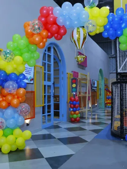 A rainbow-colored balloon arch for a transportation-themed party. The hot air balloon and police car details add a playful touch.