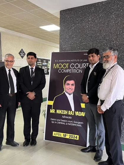 Standing beside a poster for the moot court competition where I was invited as a judge. It's a privilege to contribute to the practical training of law students.