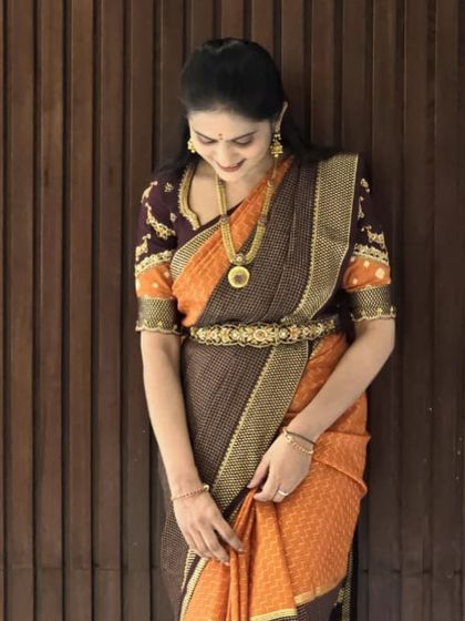 Another beautiful shot of our client in the orange and brown pure Mysore crepe silk saree, showcasing its beautiful drape and rich texture.