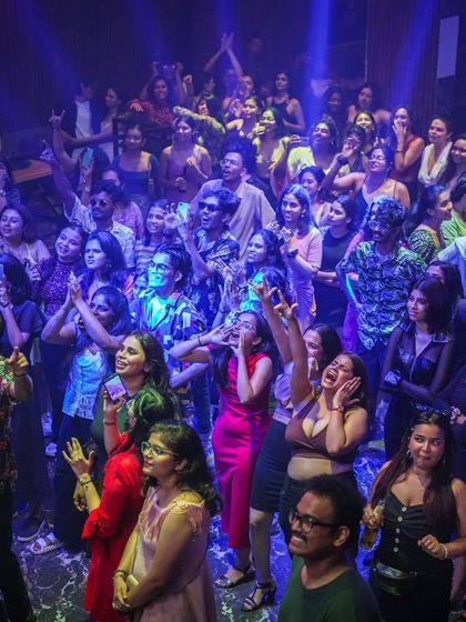 A candid shot of the crowd looking up towards the DJ booth, fully captivated by the music and the performance.
