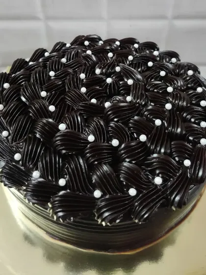 I love the challenge of creating detailed frosting designs. This rich chocolate cake features an intricate basket-weave piping technique, with each swirl carefully placed and dotted with delicate white pearls for an elegant finish.
