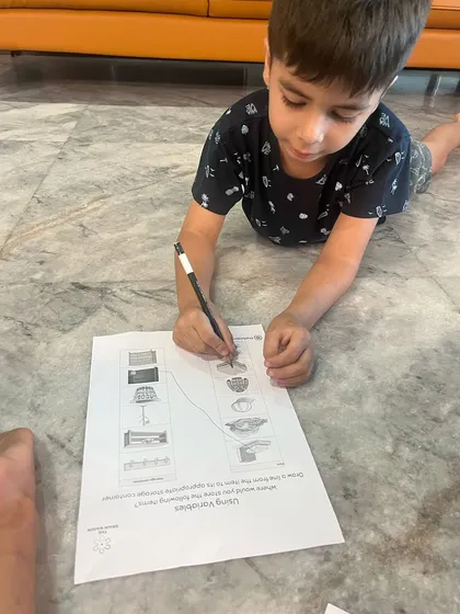 A child carefully works on a sequencing worksheet related to the roller coaster project. This activity reinforces the concept of algorithms, or step-by-step instructions, in a clear and simple format.