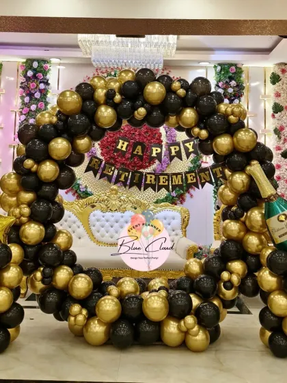 A classic black and gold balloon ring setup for a Happy Retirement party in a banquet hall.