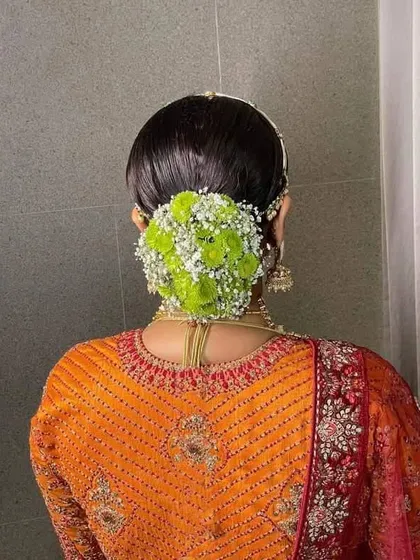 A beautiful floral bun with green and white flowers. This is a great example of how you can use unconventional flower colors to create a unique and stunning bridal look.