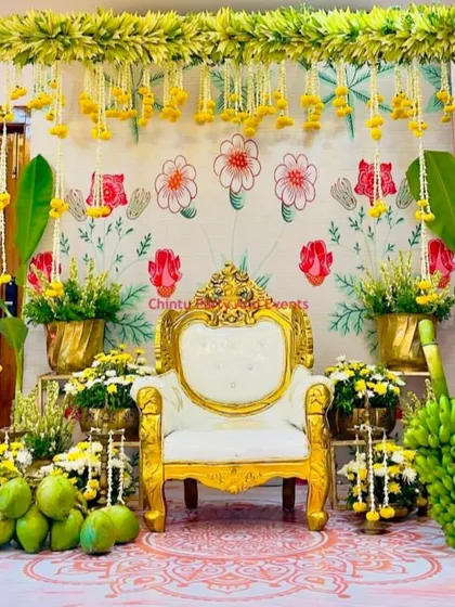 A rich and traditional baby shower (Seemantham) decoration for a home ceremony. The backdrop features banana leaves, marigolds, and a classic throne, creating an authentic and auspicious setting.
