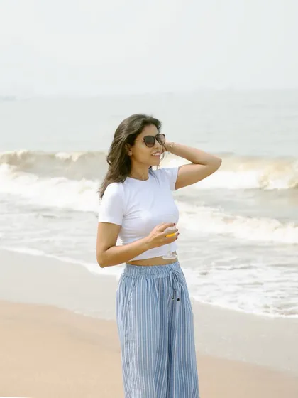 A classic beach pose, looking out at the waves. This image has a relaxed, carefree vibe and showcases the full casual outfit, making it a versatile asset for any summer fashion campaign.