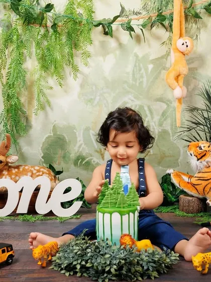 A little boy plays with his jungle-themed cake during his first birthday cake smash session.