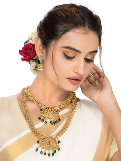 A poised and elegant shot of a model wearing a complete South Indian temple jewellery set. The focus is on the layers of necklaces and the traditional design, making it an excellent choice for a brand's main campaign image.