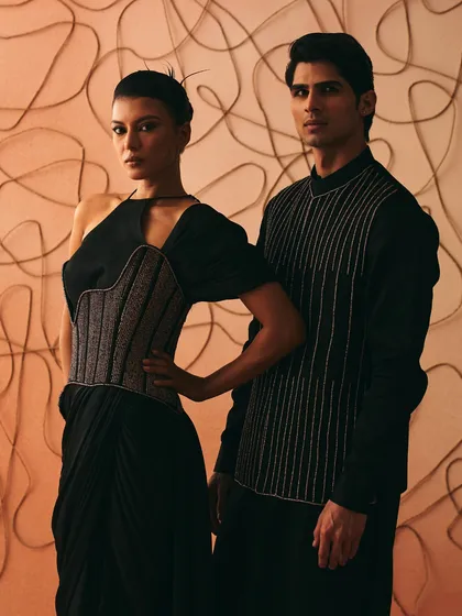The Nexus gown for her, paired with a men's tunic featuring linear embroidery. Together, they hold the weight of ties that refuse to fade.