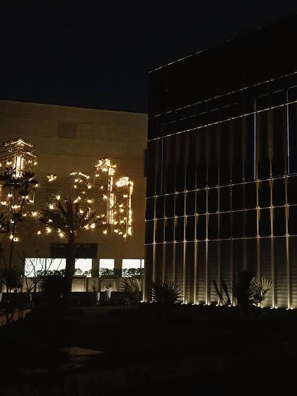 This image captures the interplay between the structured facade lighting of the main office block and the decorative lighting installation on the adjacent building, demonstrating our ability to create a cohesive lighting environment across multiple structures.